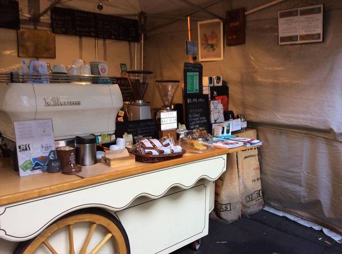 Espresso Base's canvas-covered cart, set up with the La Marzocco and menu boards